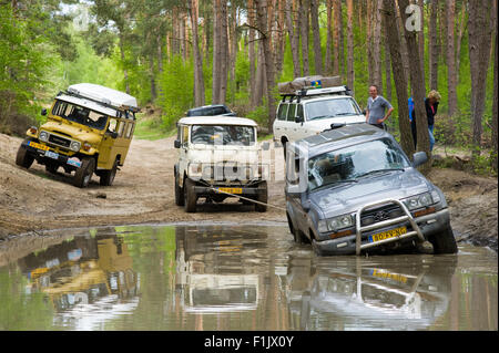 Une Toyota Land Cruiser est coincé dans un étang de l'eau sur un terrain hors de la route et les véhicules de land cruisers Banque D'Images