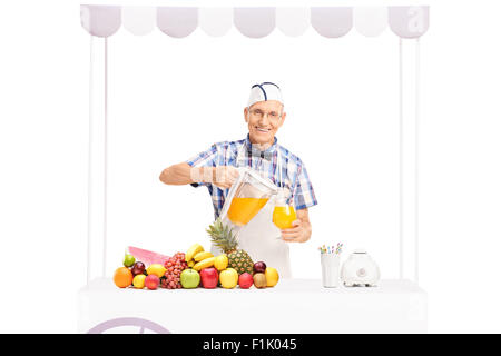 Soda pouring jerk senior dans un verre de jus d'orange et regardant la caméra isolé sur fond blanc Banque D'Images