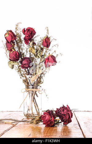 L'accent sur l'avant rose séchée et flou en bouquet de roses séchées rouge vase en verre sur fond blanc Banque D'Images