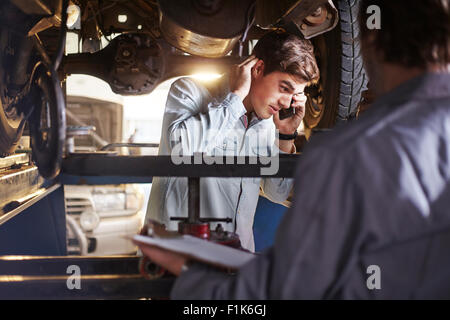 Mécanicien et customer talking on cell phone sous location Banque D'Images