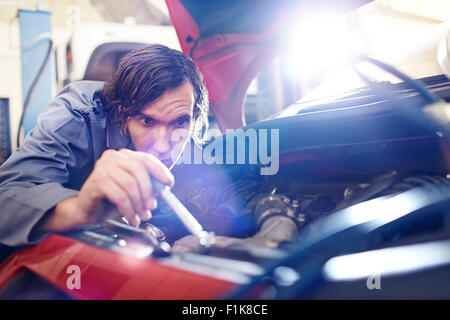 Mécanicien au service du moteur en atelier de réparation automobile Banque D'Images