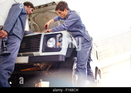 Mécaniciens travaillant sur le moteur à l'atelier de réparation automobile Banque D'Images