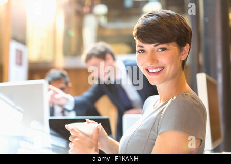 Portrait confident businesswoman drinking coffee in office Banque D'Images