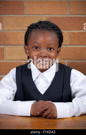 Jeune écolière africaine assis à un bureau, smiling at camera Banque D'Images