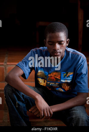 Un African teenage boy assis dehors, à la sombre Banque D'Images