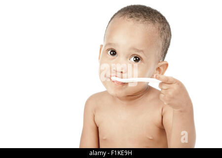 Un enfant est assis devant un fond blanc, manger. Banque D'Images