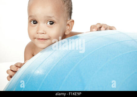 Bébé assis devant un fond blanc avec une boule d'exercice Banque D'Images
