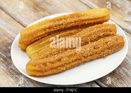 Churros sur plaque blanche sur la surface en bois rustique Banque D'Images