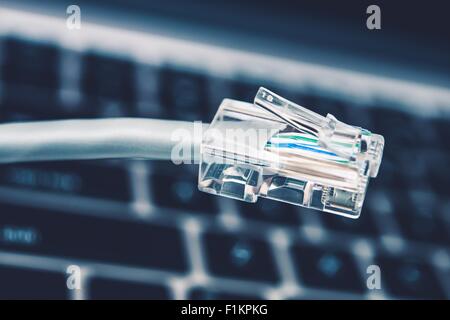 Connecteur du câble réseau RJ45 libre avec clavier à l'arrière-plan. Banque D'Images