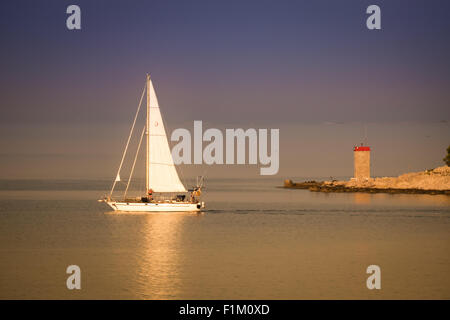 RAB, CROATIE - CIRCA AOÛT 2015 : Bateau à voile décolle tôt le matin une lumière dorée. Banque D'Images