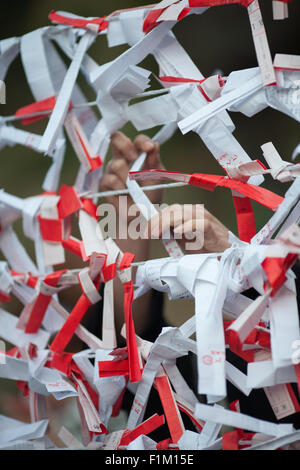 Lier la main omikuji fortune autour du fil avec de nombreux autres omikuji autour d'elle. Banque D'Images