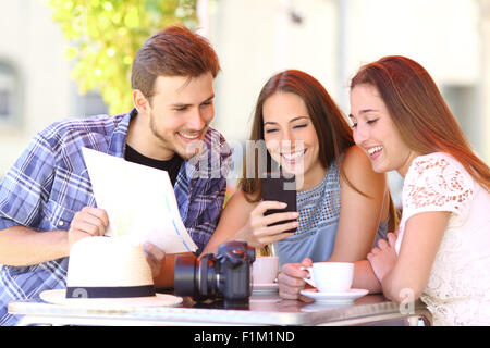 Groupe de trois amis tourisme vacances de planification avec un téléphone gps et une carte dans un café Banque D'Images