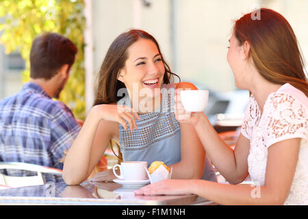 Deux amis ou sœurs parler en tenant une conversation dans un café terrasse à l'autre Banque D'Images