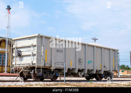 Wagon-trémie fer rempli de pierres concassées stone en stationnement sur voie de garage en face de railroad railway depot à Bertram Texas Banque D'Images