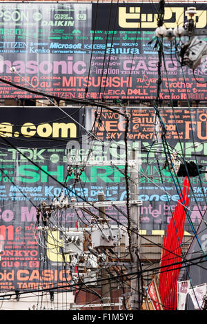 Osaka. Dotonbori. Câbles électriques aériens vue à l'extérieur d'un mur recouvert de panneaux publicitaires pour les compagnies électriques, Casio, Panasonic etc. Banque D'Images