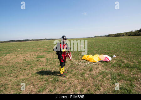 Cette fille débarque avec son parachutiste parachute et est maintenant très heureux d'être enregistrer sur le sol. Banque D'Images