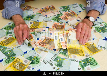 Un homme âgé avec beaucoup de billets sur la table Banque D'Images