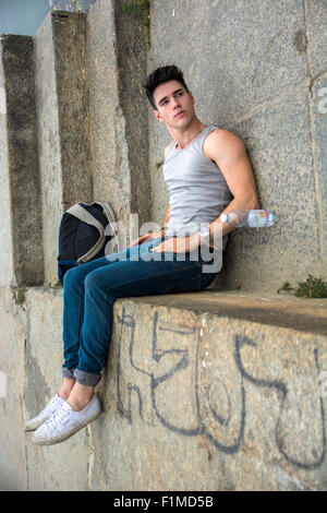 Jeune homme avec sac à dos et une bouteille d'eau étendue sur le sol près de l'escalier - truc, Impossible Illusion, Image tourné pour apparaître un Banque D'Images