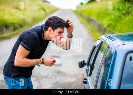 Moitié du corps, prise d'un beau jeune homme en regardant son reflet sur la fenêtre d'une voiture et fixant ses cheveux. Banque D'Images