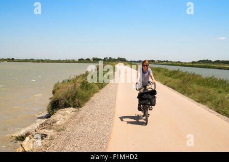 Cycliste féminine à cheval le long de la piste cyclable entre Aigues-Mortes et Le Grau-du-Roi, Languedoc-Roussillon, France, Europe Banque D'Images