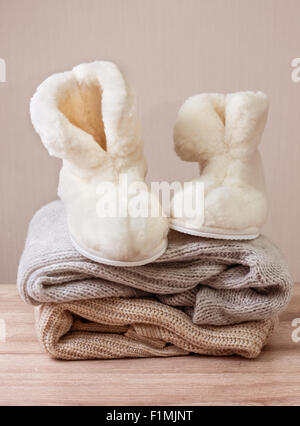Paire de Chaussons en peau de mouton d'hiver chaud (alpaga) sur le tas de vêtements en laine chaude (Selective focus) Banque D'Images