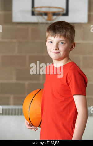 Portrait Of Boy Holding Basket-ball au gymnase de l'école Banque D'Images