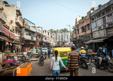 Indian couple holding hands and walking down une rue animée dans le quartier de Paharganj New Delhi, Inde Banque D'Images