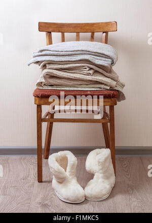 Pile de vêtements chauds sur la chaise, paire de chaussons en peau de mouton d'hiver chaud Banque D'Images