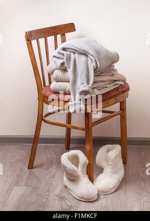 Pile de vêtements chauds sur la chaise, paire de chaussons en peau de mouton d'hiver chaud Banque D'Images