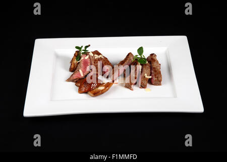 Boeuf aux champignons en plaque blanche sur fond noir Banque D'Images