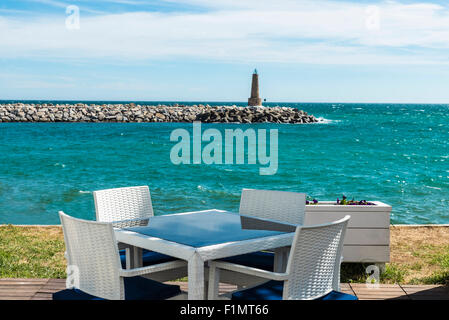 Bar où vous pourrez prendre un verre en regardant la mer avec le phare en pierre à la fin de la jetée de Puerto Banus, Marbella, Espagne Banque D'Images