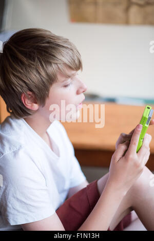 Blanc, blond-haired girl in a White T-shirt et short joue sur une machine vintage lime green Gameboy Banque D'Images