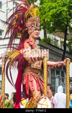 Un danseur portant des vêtements exotiques debout sur le flotteur et la danse comme parade passe par le quartier de Notting Hill et Ladbroke Grove Banque D'Images