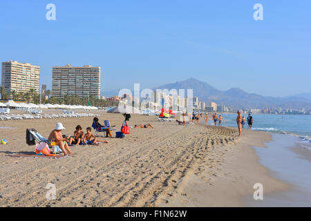 Le long de la plage à Playa de San Juan en direction de Campello, avec des gens se baigner de soleil, tôt le matin. Alicante, Espagne Banque D'Images