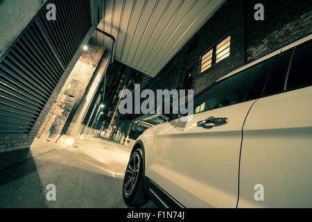 Concept de la conduite urbaine. Vus blanc voiture sur la ville américaine Alley dans la nuit. Banque D'Images