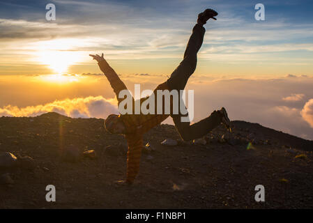 L'homme sauter à travers l'écart sur sunset fiery arrière-plan. Élément de design. Banque D'Images