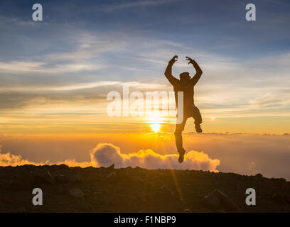 L'homme sauter à travers l'écart sur sunset fiery arrière-plan. Élément de design. Banque D'Images