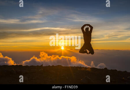 L'homme sauter à travers l'écart sur sunset fiery arrière-plan. Élément de design. Banque D'Images