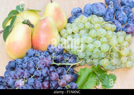 Les raisins, poires et prunes sur une table en bois Banque D'Images