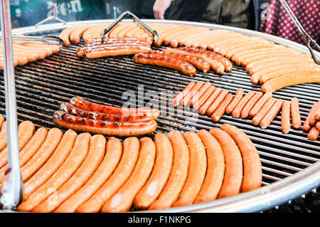 Saucisses, saucisses Bratwurst et cuisson sur un grand barbecue dans une échoppe de marché Banque D'Images