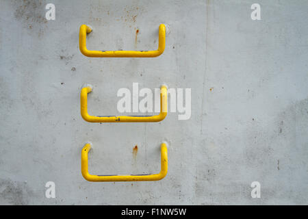 Les échelles de fer peint jaune monté sur mur de béton. Banque D'Images