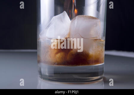 Rum étant versé sur de la glace et la vodka en verre clair Banque D'Images