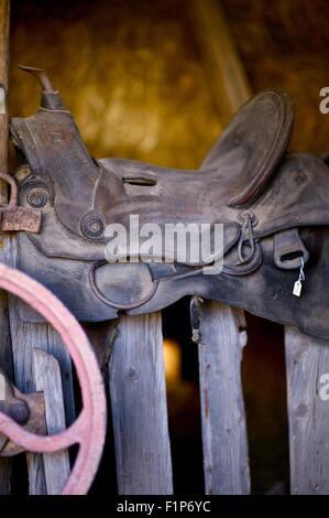 Selle sur une barrière en bois. Siège cheval sur plancher bois dans la grange. Photo verticale. Banque D'Images