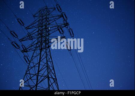Pylône à haute tension de l'électricité avec du vrai Ciel de nuit avec de nombreuses stars - photos à longue exposition. Les lignes de transport d'énergie. Banque D'Images