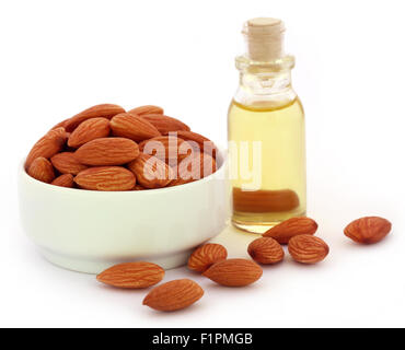 Amandes fraîches avec une bouteille de l'huile sur fond blanc Banque D'Images