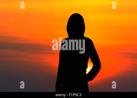 Silhouette de la jeune fille dans les vêtements de sport avec une capuche au coucher du soleil Banque D'Images