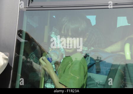 Pirée, Grèce. 06 Sep, 2015. Un garçon regarde par une fenêtre de l'autobus. Tera Jet ferry est arrivé au port de Pirée transportant 1700 réfugiés syriens de l'île grecque de Lesbos. Crédit : George/Panagakis Pacific Press/Alamy Live News Banque D'Images