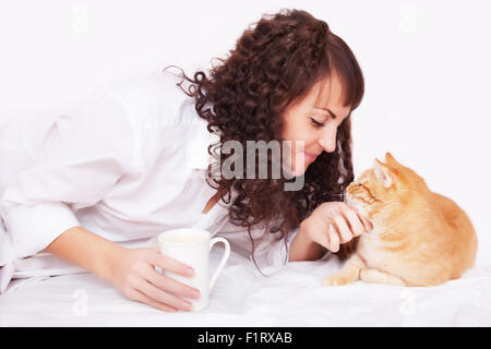 Fille avec une tasse de café et un chat dans le lit Banque D'Images