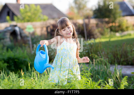 Cute little girl watering plants dans le jardin Banque D'Images