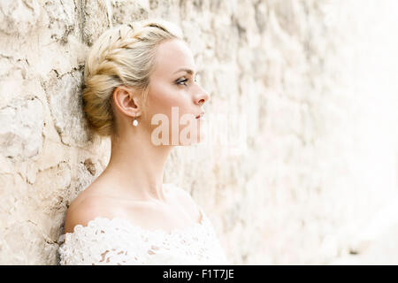 Portrait de mariée leaning against wall Banque D'Images